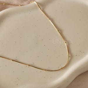 May include: A gold chain necklace with small round beads spaced evenly along the chain.