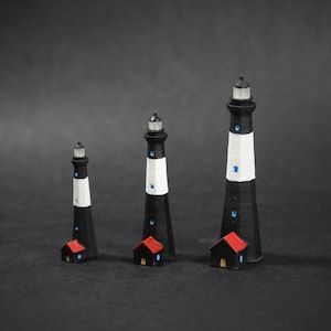 May include: Three black and white lighthouse figurines with red roofs, arranged in order of size from smallest to largest.