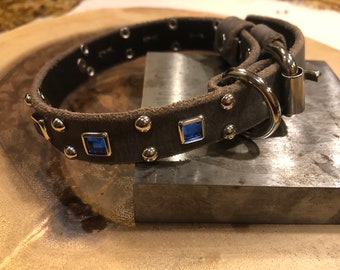 May include: A brown leather dog collar with silver studs and blue square rhinestones.