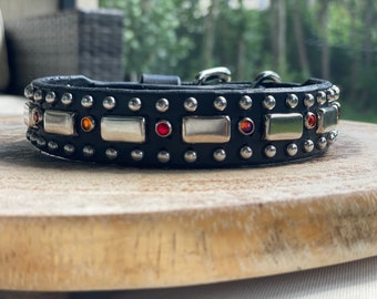 May include: Black leather dog collar with silver studs and red and orange gemstones.