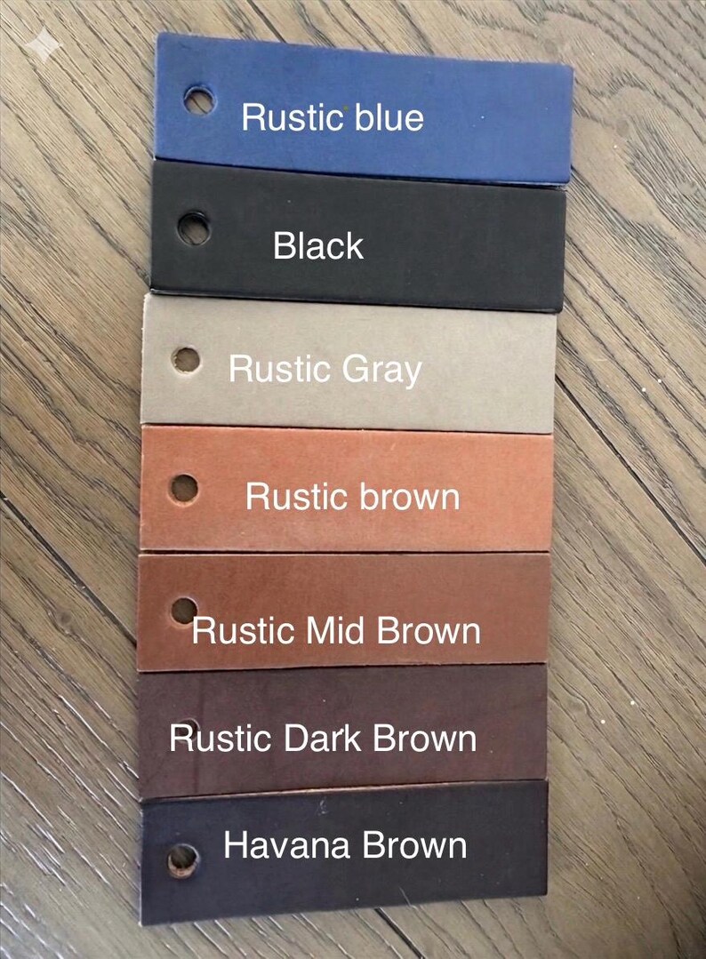 May include: A set of seven rectangular leather swatches arranged in a vertical column, each featuring a circular hole on the left side. The colors are labeled as Rustic blue, Black, Rustic Gray, Rustic brown, Rustic Mid Brown, Rustic Dark Brown, and Havana Brown.