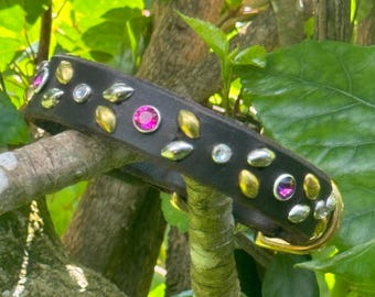 May include: A black leather dog collar with gold and silver studs and pink rhinestones.