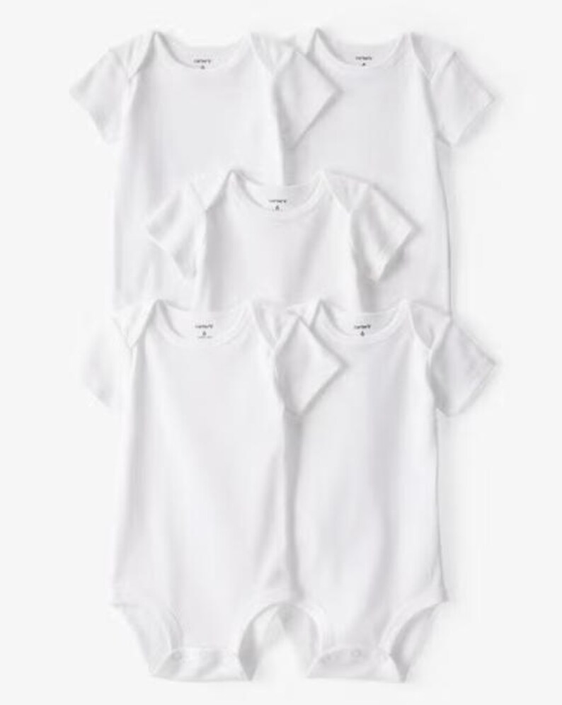 May include: Six white baby bodysuits with short sleeves are stacked. The bodysuits are plain and have a simple design. The brand name "Carter's" is printed on the front of each bodysuit.