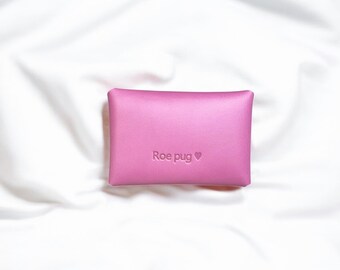 May include: A pink leather pouch with the text "Roe pug" and a heart symbol embossed on the front.