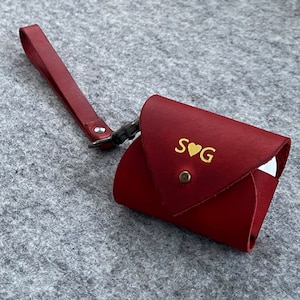 May include: A red leather key chain with a gold heart and the initials "S♥G" embossed on the front.