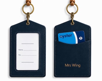 May include: A navy blue leather ID badge holder with a tan leather neck strap and brass hardware. The front features a clear window with a white insert labeled Name and No. The back has a pocket containing a blue Oyster card and the text Mrs Wing.