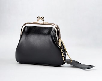May include: A black leather coin purse with a gold-toned frame and a chain attached. The purse has a rounded shape and a smooth finish.