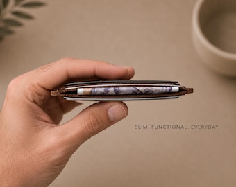 May include: A slim brown leather card holder with visible stitching along the edges, containing several cards and a folded banknote. The text SLIM. FUNCTIONAL. EVERYDAY. is printed in small black capital letters on the right side of the object.