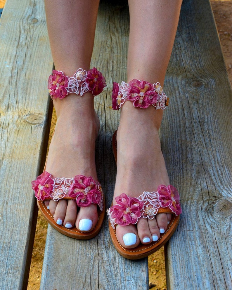 K&ouml;nnte beinhalten: Rosa und wei&szlig;e Blumensandalen mit Ledersohle. Die Sandalen haben ein zartes, feminines Design und sind perfekt f&uuml;r den Sommer.