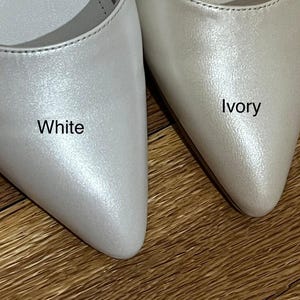 Op de afbeelding: Twee paar spitse schoenen in wit en ivoor. De schoenen zijn gemaakt van een glanzend, parelmoerachtig materiaal. Het woord "Wit" staat op de linker schoen en het woord "Ivoor" op de rechter schoen.