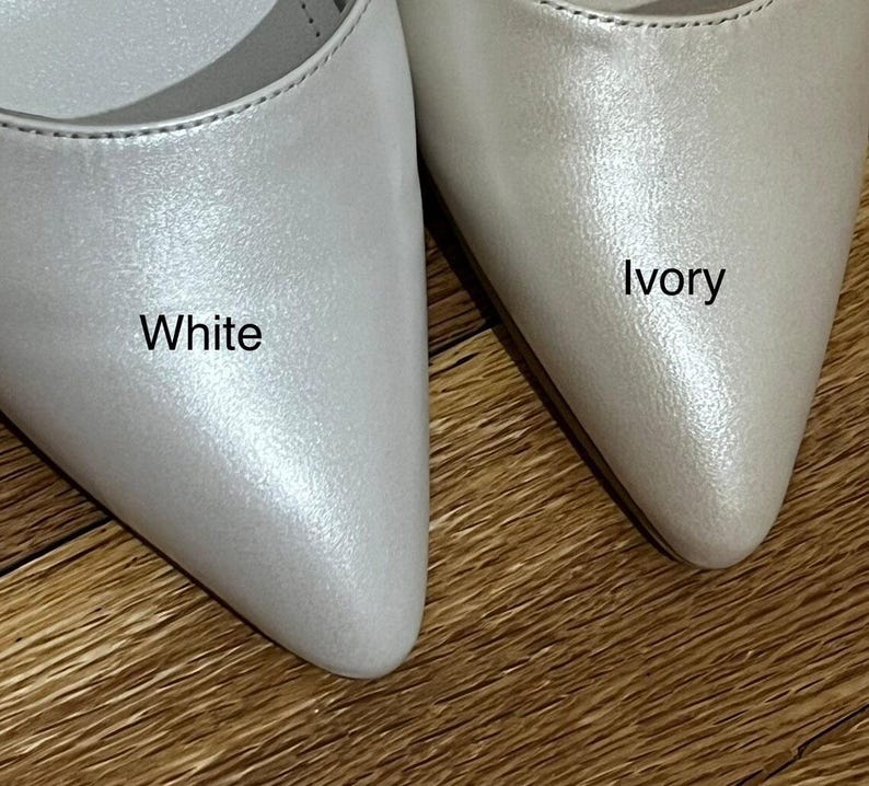 Op de afbeelding: Twee paar spitse schoenen in wit en ivoor. De schoenen zijn gemaakt van een glanzend, parelmoerachtig materiaal. Het woord "Wit" staat op de linker schoen en het woord "Ivoor" op de rechter schoen.