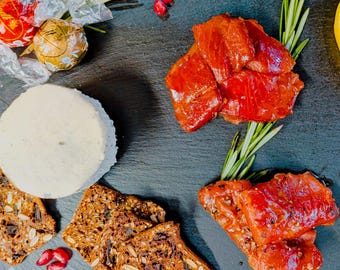 Confezione regalo natalizia con salmone affumicato: bocconcini di salmone rosso selvatico e acero e bocconcini di salmone affumicato al pepe selvatico con cracker, cioccolatini e formaggio Boursin