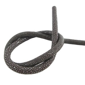 Puede incluir: Un cordón de cuero de raya gris oscuro atado en un nudo simple. El material presenta una textura granulada y perlada característica del cuero de raya, con una coloración oscura uniforme a lo largo de toda la longitud del cordón.