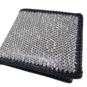 Peut inclure: Un portefeuille pliable doté d'un panneau extérieur texturé à motif peau de serpent gris et blanc. Les bords du portefeuille sont finis avec une épaisse bordure en cuir tressé noir qui encadre la section centrale à motifs sur tous les côtés.