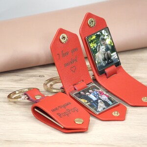 May include: Red leather keychains with a photo display. One keychain is open, revealing a photo of a person with a dog. The text "I love you mostest" is engraved on the keychain. Another keychain has the text "we ❤️ you PopPop".