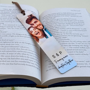 May include: A silver bookmark with a photo of a couple smiling. The bookmark has the text "S&P To many more chapters together" printed on it.