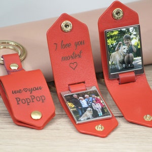 K&ouml;nnte beinhalten: Rote Leder-Schl&uuml;sselanh&auml;nger mit goldfarbener Hardware. Ein Schl&uuml;sselanh&auml;nger hat den Text "we love you PopPop". Zwei Schl&uuml;sselanh&auml;nger haben den Text "I love you mostest" und ein Foto. Ein Schl&uuml;sselanh&auml;nger hat ein Foto von einem Jungen und einem Hund.