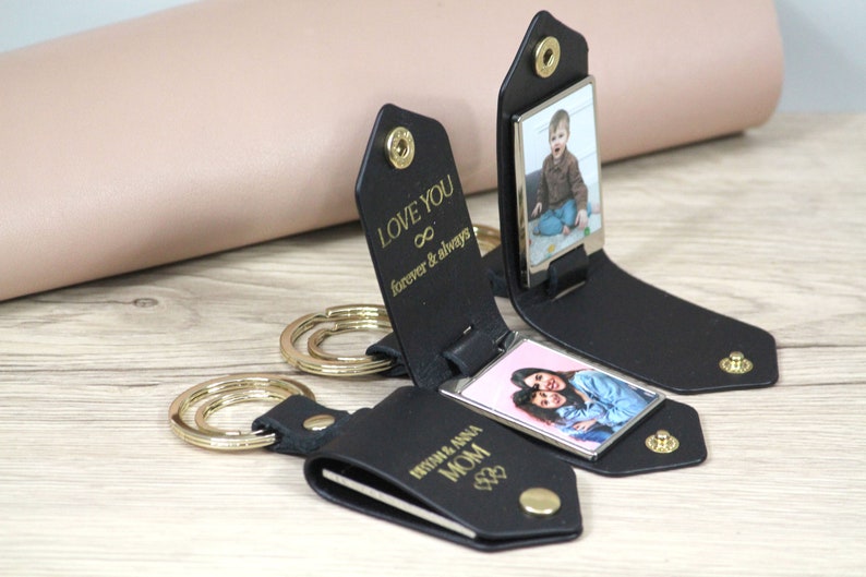 May include: Black leather keychains with gold hardware and photo inserts. One keychain reads "LOVE YOU forever & always". Another reads "RYSHM & ANNA MOM". The keychains display photos of people.
