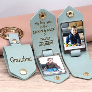 May include: A light blue leather keychain with a gold keyring and snap closure. One keychain is engraved with "Grandma." Two other keychains have a photo and the engraved text "We love you to the MOON & BACK" with names. The keychains are personalized.