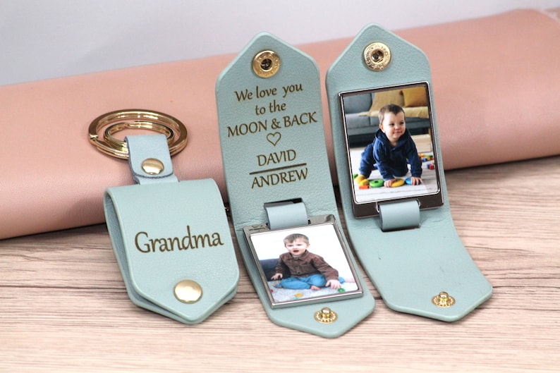 May include: A light blue leather keychain with a gold keyring and snap closure. One keychain is engraved with "Grandma." Two other keychains have a photo and the engraved text "We love you to the MOON & BACK" with names. The keychains are personalized.