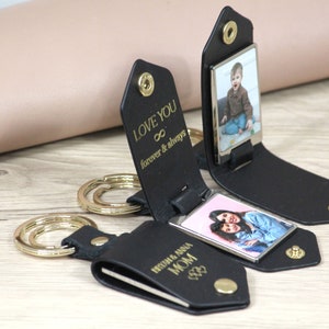 K&ouml;nnte beinhalten: Schwarze Leder-Schl&uuml;sselanh&auml;nger mit goldenen Beschl&auml;gen und Fotoeins&auml;tzen. Auf einem Schl&uuml;sselanh&auml;nger steht "LOVE YOU forever & always". Ein anderer tr&auml;gt die Aufschrift "RYSHM & ANNA MOM".