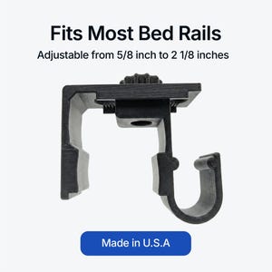 Op de afbeelding: Een zwarte bedrails beugel, verstelbaar van 1,6 cm tot 5,4 cm, met de tekst "Fits Most Bed Rails". De beugel heeft een haakvorm en is gemarkeerd met "Made in U.S.A."
