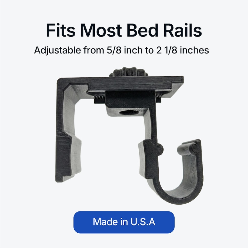 Op de afbeelding: Een zwarte bedrails beugel, verstelbaar van 1,6 cm tot 5,4 cm, met de tekst "Fits Most Bed Rails". De beugel heeft een haakvorm en is gemarkeerd met "Made in U.S.A."