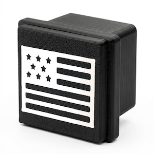 May include: A black, rectangular hitch cover featuring a white American flag design. The flag includes seven stars and horizontal stripes. The hitch cover is made of a durable material and is designed to protect the hitch receiver.