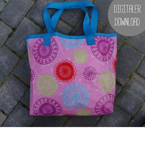 Könnte beinhalten: Eine rosa Tragetasche mit einem blauen Henkel und einem Blumenmuster. Das Muster zeigt rosa, rote, blaue und grüne Kreise auf weißem Hintergrund.
