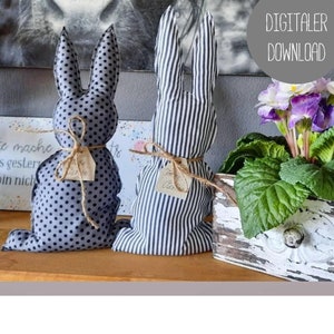 Könnte beinhalten: Zwei handgemachte Stoff-Osterhasen, einer mit schwarzen und weißen Punkten und der andere mit schwarzen und weißen Streifen. Beide Hasen sind mit Schnur gebunden und haben ein kleines Etikett befestigt.