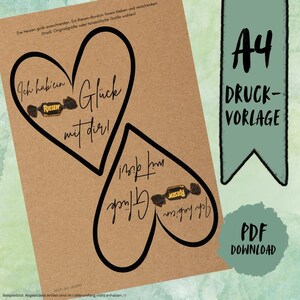 May include: A4 printable template on kraft paper with two heart outlines. Each heart contains the German text "Ich hab' ein Glück mit dir!" and a candy graphic. A green banner reads "A4 Druckvorlage" and "PDF Download".