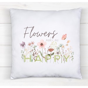 Könnte beinhalten: Weißes quadratisches Kissen mit floralem Design und dem Schriftzug "Flowers make me HAPPY". Das Design zeigt Aquarellblumen in Rosa, Lila und Gelb, mit einem Schmetterling. Ein dekoratives Element für ein Wohn- oder Schlafzimmer.