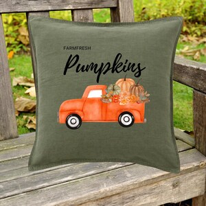 Könnte beinhalten: Ein grünes Kissen mit einem roten Lastwagen, der Kürbisse transportiert, und dem Text "Farm Fresh Pumpkins".