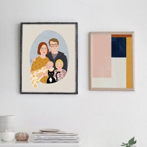 以下が含まれることがあります： 黒い猫と4人家族のイラストが額装されています。家族は円になって立っており、両親が後ろ、2人の子供が前にいます。両親は真ん中に赤ちゃんを抱いています。イラストはベージュの背景に青と白のパターンが描かれています。