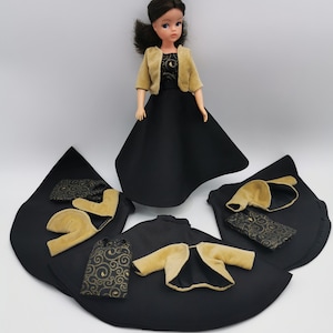 May include: A black and gold doll outfit with a black dress, a gold jacket, and a black and gold purse. The doll is not included.
