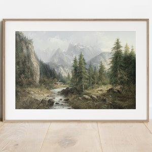 May include: A framed painting depicting a mountain landscape with a river flowing through a forest. The mountains are snow-capped and the trees are green. A small cabin is visible in the distance.