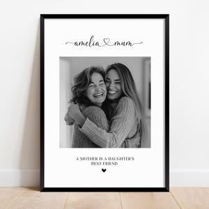 K&ouml;nnte beinhalten: Schwarzwei&szlig;foto von zwei Frauen, die sich umarmen. Das Foto ist in einem schwarzen Rahmen mit dem Text "amelia &hearts; mum" und "A mother is a daughter's best friend" unter dem Foto.