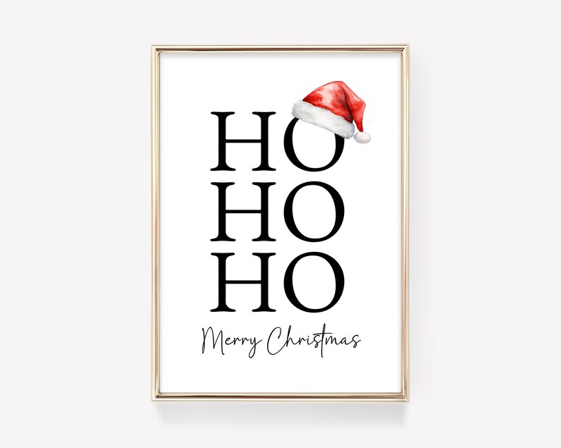 May include: A white printable art print with a gold frame. The print features the words "HO HO HO" in black text and the words "Merry Christmas" in cursive text. A red and white Santa hat is at the top of the print.