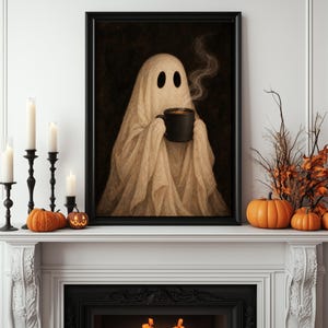 May include: A framed wall art print featuring a beige ghost draped in a sheet, holding a black mug with rising steam. The ghost has two dark oval eyes and is set against a dark background. The artwork is displayed on a white fireplace mantel.