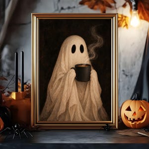 May include: A framed wall art print featuring a white ghost draped in a sheet, holding a black mug with rising steam. The ghost has two dark oval eyes and is set against a dark background. The frame is metallic gold with a simple border design.