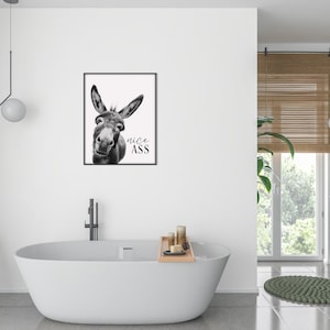 K&ouml;nnte beinhalten: Schwarz-Wei&szlig;-Druck eines Esels mit dem Text "nice ASS". Das Kunstwerk wird in einem modernen Badezimmer &uuml;ber einer wei&szlig;en Badewanne ausgestellt. Der Raum verf&uuml;gt auch &uuml;ber ein Fenster mit Jalousien.