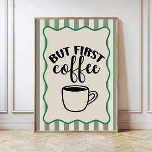 Può includere: Opera d'arte da parete incorniciata con la scritta "BUT FIRST coffee" in nero sopra un'illustrazione di tazza di caffè nera. L'opera ha uno sfondo beige con un bordo verde ondulato ed è ambientata su uno sfondo a righe verdi e bianche.