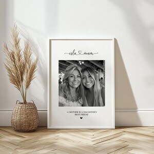 K&ouml;nnte beinhalten: Schwarzwei&szlig;foto von zwei Frauen, einer Mutter und ihrer Tochter, mit dem Text "isla & mum" und "Eine Mutter ist die beste Freundin ihrer Tochter" auf wei&szlig;em Hintergrund.