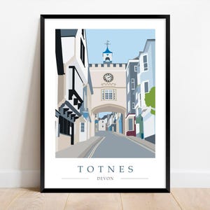 Peut inclure: Impression d'art encadrée de Totnes, Devon, représentant une scène de rue avec un clocher et une arche. L'œuvre utilise un style minimaliste avec des couleurs sourdes, notamment le bleu, le gris et le beige. Le nom de la ville est imprimé en bas.