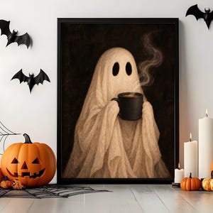 May include: A framed wall art print featuring a beige ghost draped in fabric, holding a steaming black mug against a dark background. The ghost has two large oval eyes and is centered within a simple black frame, showcasing a spooky aesthetic.