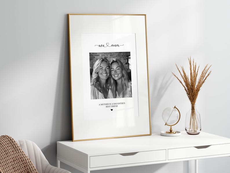 K&ouml;nnte beinhalten: Schwarzwei&szlig;foto von zwei Frauen, einer Mutter und ihrer Tochter, mit dem Text "Eine Mutter ist die beste Freundin ihrer Tochter" und einem Herzsymbol unter dem Foto. Das Foto ist in einem goldenen Rahmen gerahmt und steht auf einem wei&szlig;en Tisch.