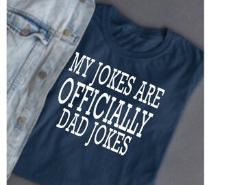 May include: A navy blue t-shirt with white text that reads "My jokes are officially dad jokes".