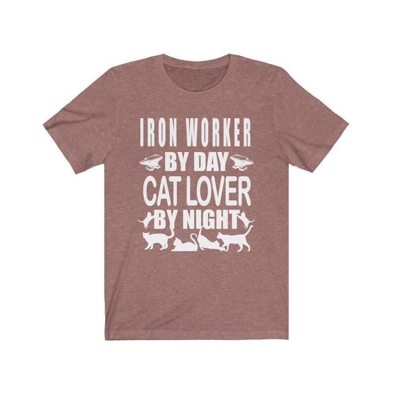 May include: A heather brown t-shirt with the text "Iron Worker By Day Cat Lover By Night" in white. The text is surrounded by images of cats and an anvil.