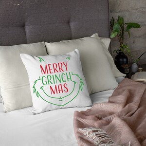 May include: White throw pillow with green and red text that reads "Merry Grinch Mas" and a green Grinch-like face graphic.