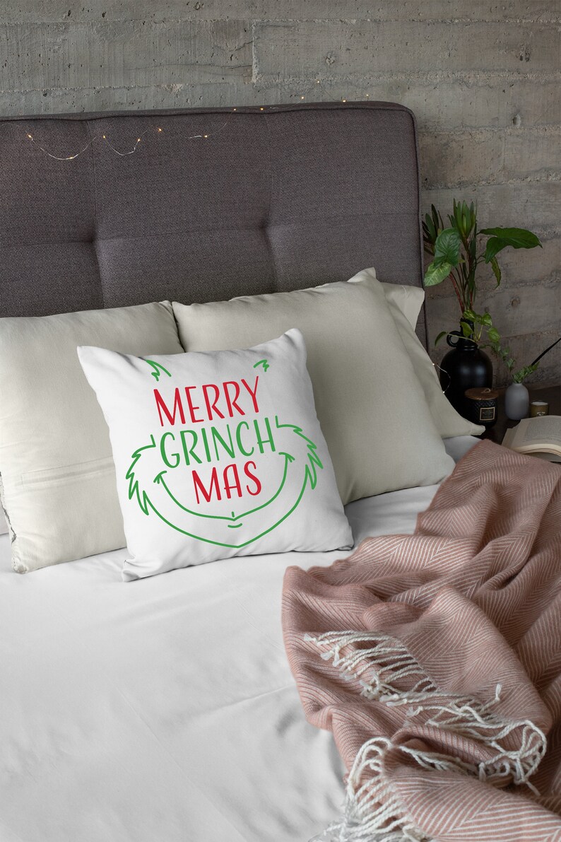 May include: White throw pillow with green and red text that reads "Merry Grinch Mas" and a green Grinch-like face graphic.
